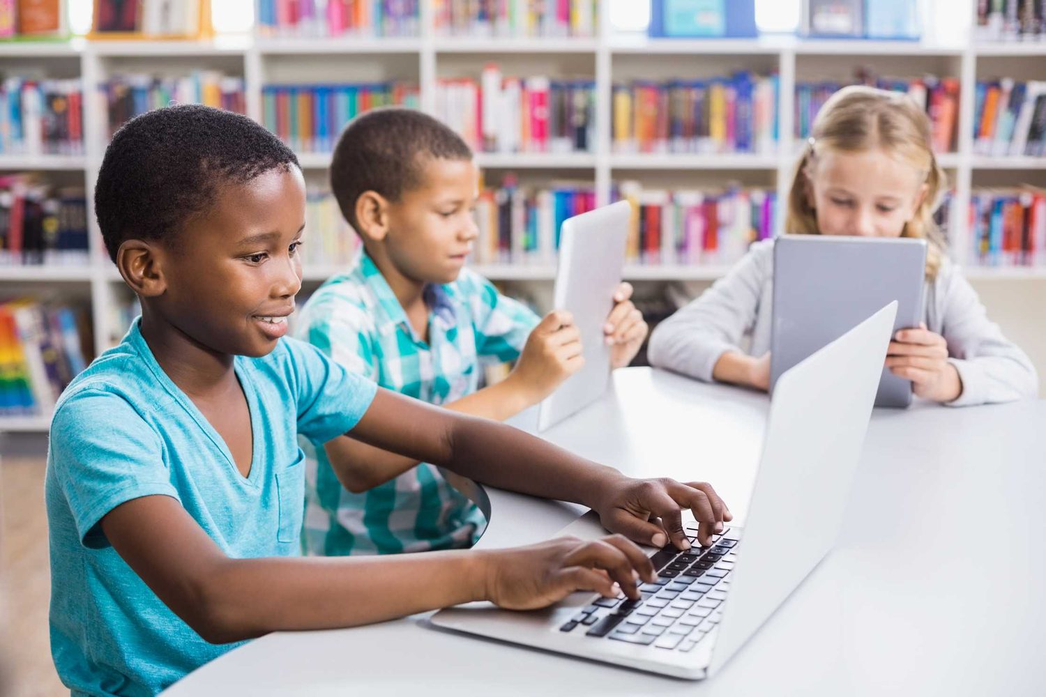Children using a laptop and tablet in a library