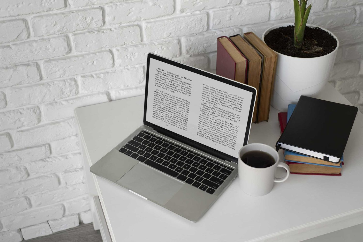 An overhead view of a laptop surrounded by open books